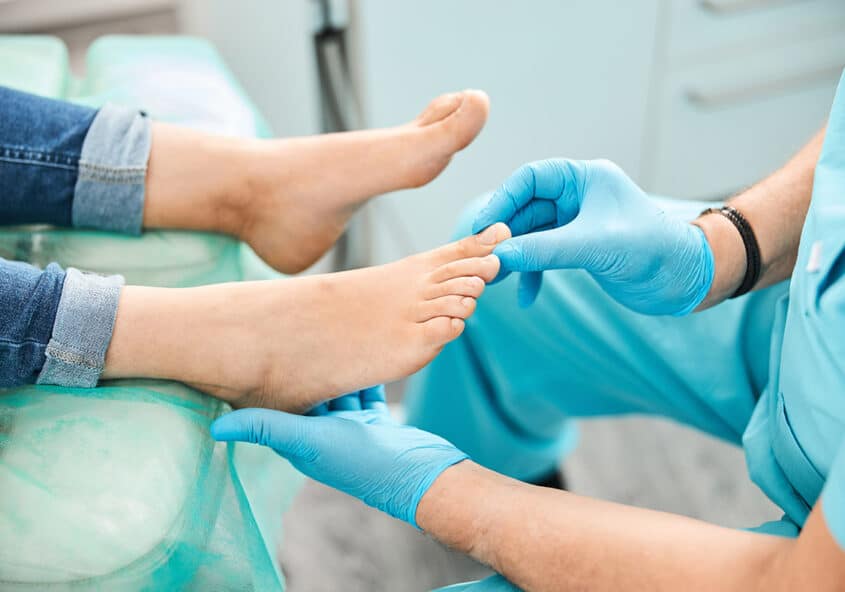 Un podólogo con guantes azules examina el pie y los dedos de un paciente durante una consulta en Metro Healthcare Partners, en Brooklyn (Nueva York).