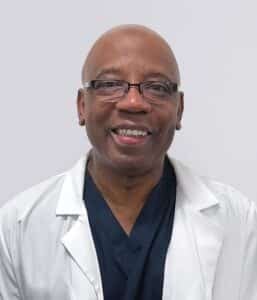 Dr. Billy Ford - Experienced Pain Management Specialist Доктор Билли Форд, сертифицированный специалист по лечению боли в клинике Metro Health NYC, улыбается на профессиональном портретном снимке в белом халате